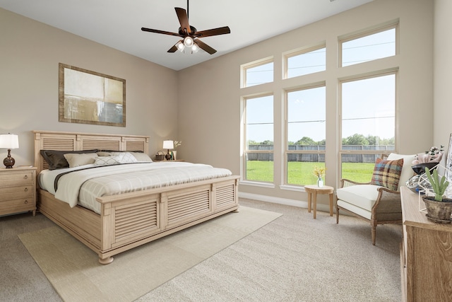 bedroom featuring ceiling fan, light colored carpet, and multiple windows