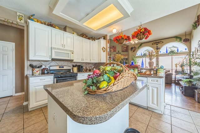 kitchen with white cabinets, stainless steel gas stove, tasteful backsplash, and a kitchen island