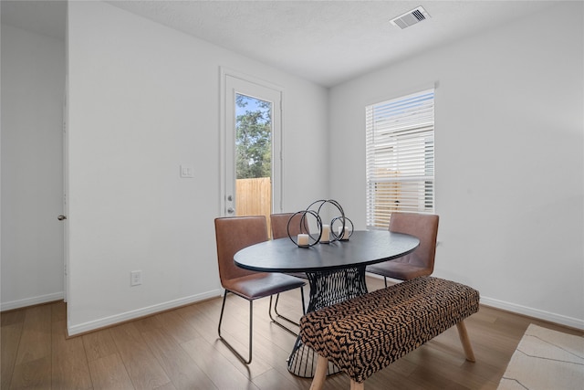 dining space with light hardwood / wood-style floors and a textured ceiling