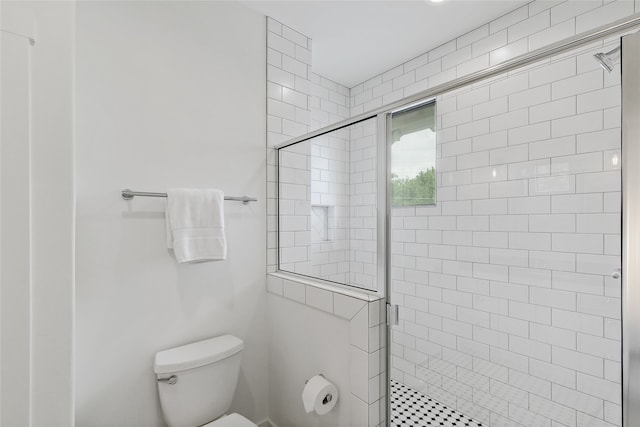 bathroom featuring a shower with door and toilet