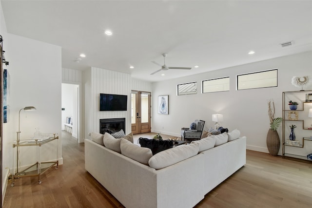 living room featuring a large fireplace, ceiling fan, and hardwood / wood-style floors