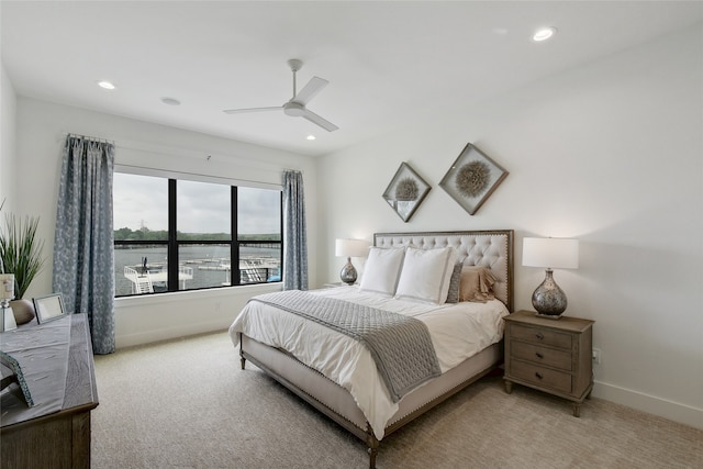 carpeted bedroom featuring a water view and ceiling fan