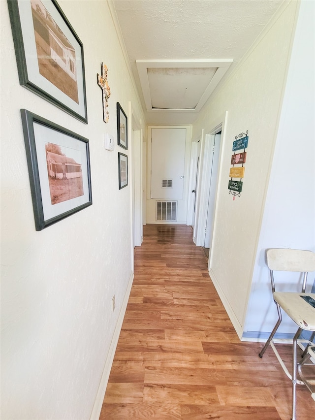 hallway with light wood-type flooring and ornamental molding