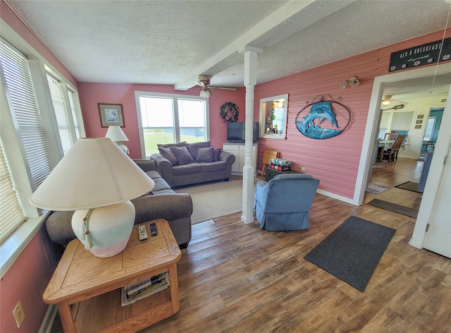 living room featuring ornate columns, a textured ceiling, ceiling fan, wood-type flooring, and vaulted ceiling with beams