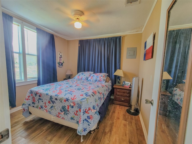 bedroom with hardwood / wood-style floors, ceiling fan, ornamental molding, and multiple windows