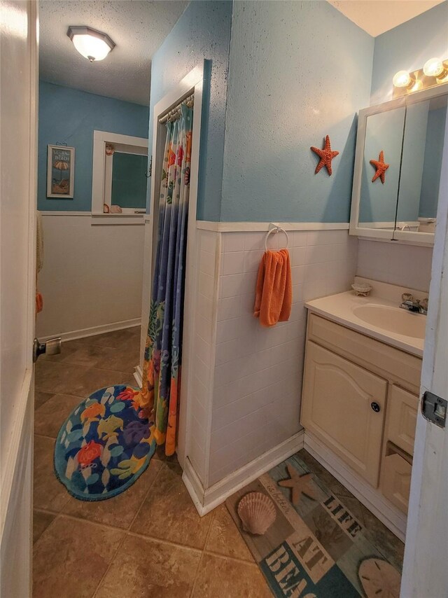 bathroom featuring tile walls, tile patterned flooring, vanity, and a textured ceiling