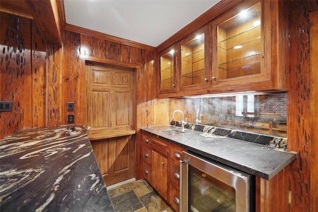 kitchen with beverage cooler, glass insert cabinets, brown cabinets, wood walls, and backsplash