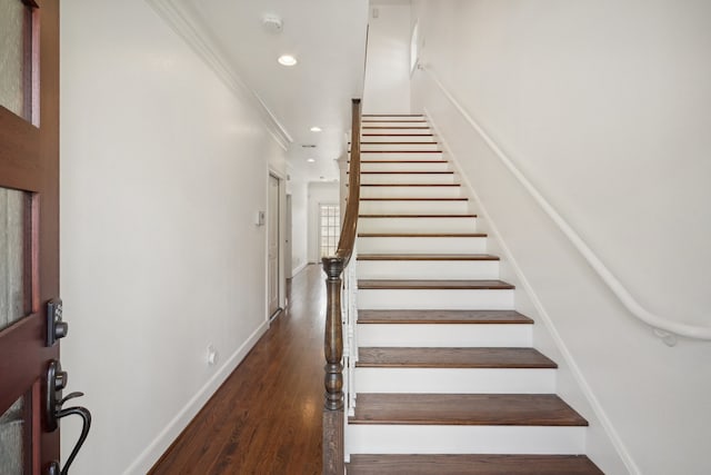 stairs featuring ornamental molding and dark hardwood / wood-style flooring