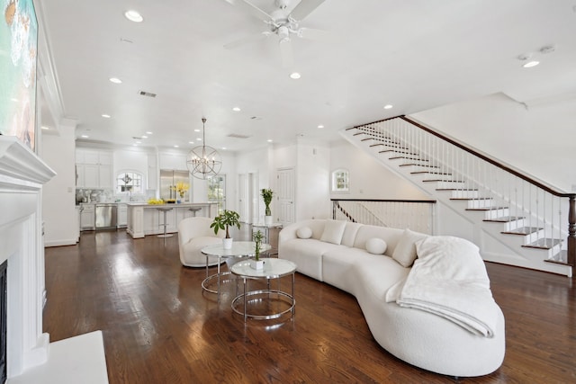 living room featuring dark hardwood / wood-style flooring, ceiling fan with notable chandelier, and crown molding