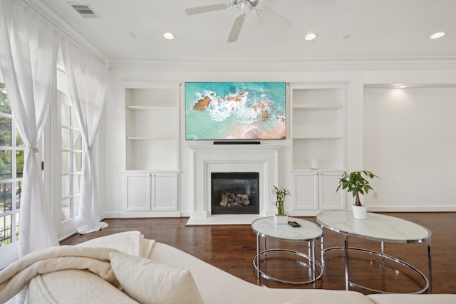 living room with built in features, ornamental molding, a healthy amount of sunlight, and dark hardwood / wood-style floors