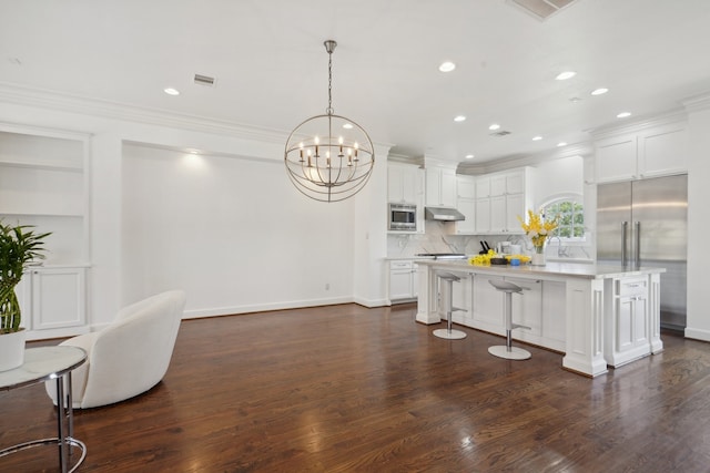 kitchen featuring built in appliances, a center island, tasteful backsplash, and dark wood-type flooring