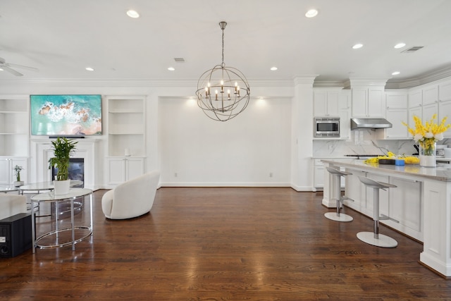 kitchen featuring stainless steel microwave, white cabinets, ceiling fan with notable chandelier, backsplash, and dark hardwood / wood-style floors