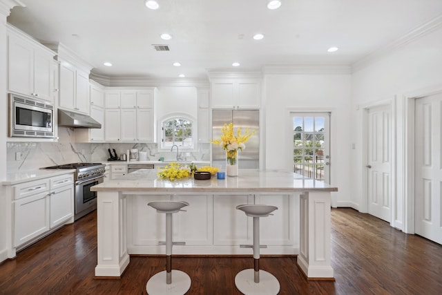 kitchen featuring backsplash, dark hardwood / wood-style flooring, a kitchen island, and built in appliances