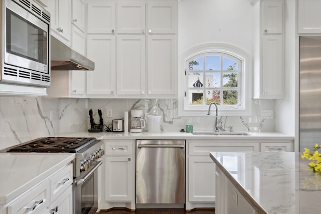 kitchen with white cabinets, wall chimney exhaust hood, appliances with stainless steel finishes, and sink