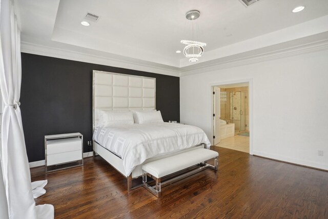 bedroom featuring an inviting chandelier, ensuite bath, hardwood / wood-style flooring, and a raised ceiling