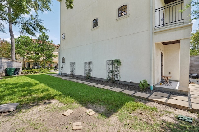 view of home's exterior with a balcony and a yard