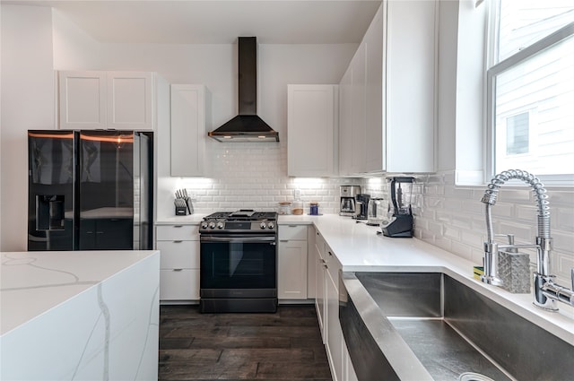 kitchen with wall chimney range hood, dark wood-type flooring, black appliances, sink, and tasteful backsplash