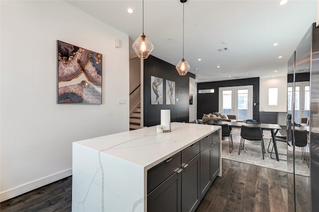 kitchen featuring a center island, dark hardwood / wood-style flooring, pendant lighting, and light stone countertops