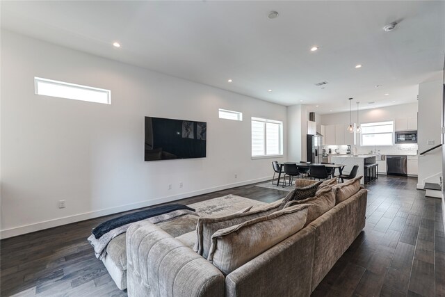 living room featuring dark hardwood / wood-style floors, plenty of natural light, and an inviting chandelier