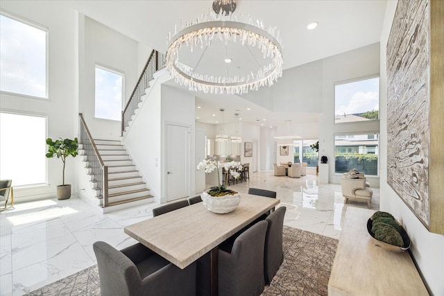 tiled dining area featuring a healthy amount of sunlight, a towering ceiling, and a chandelier