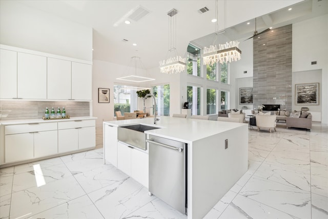 kitchen with dishwasher, decorative light fixtures, light tile floors, a kitchen island with sink, and white cabinetry