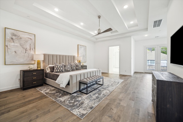 bedroom featuring ceiling fan, a tray ceiling, dark hardwood / wood-style floors, and access to outside