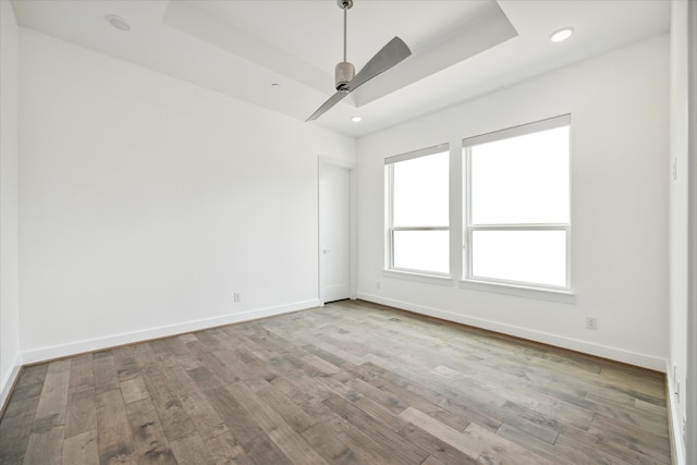 spare room with hardwood / wood-style flooring, ceiling fan, and a tray ceiling