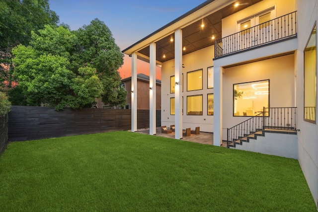 yard at dusk featuring a balcony