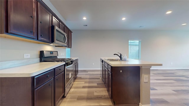 kitchen with sink, stainless steel appliances, light hardwood / wood-style flooring, a kitchen island with sink, and dark brown cabinets