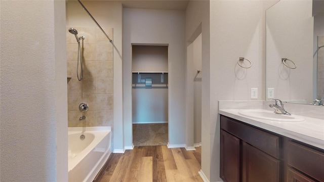 bathroom with vanity, wood-type flooring, and tiled shower / bath