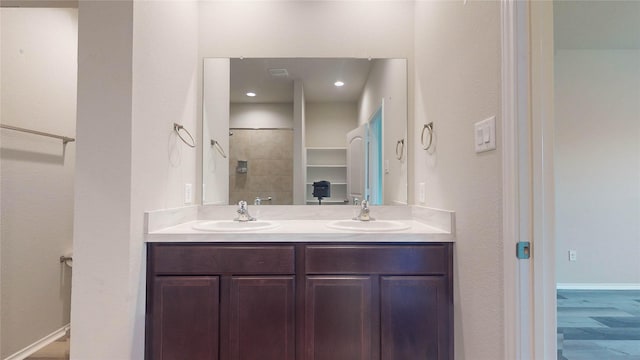 bathroom featuring vanity, wood-type flooring, and tiled shower