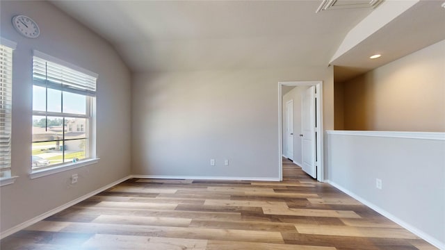 unfurnished room with lofted ceiling and light wood-type flooring