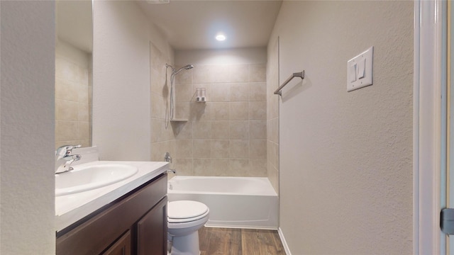 full bathroom featuring toilet, vanity, wood-type flooring, and tiled shower / bath