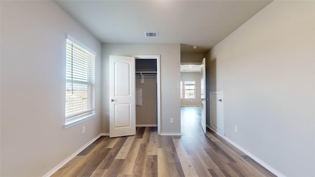 unfurnished bedroom featuring dark hardwood / wood-style floors, a closet, and multiple windows