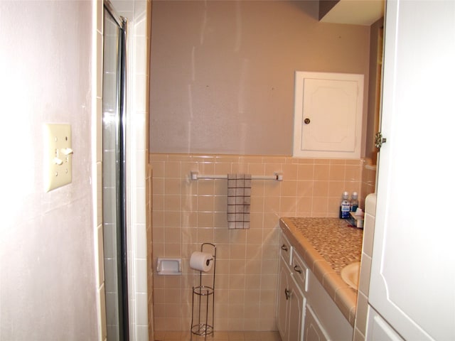 bathroom featuring tile walls, a shower with shower door, and vanity