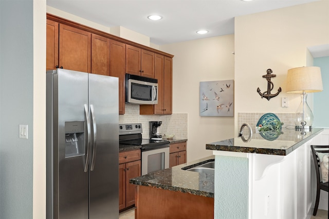 kitchen with dark stone counters, kitchen peninsula, tasteful backsplash, stainless steel appliances, and a breakfast bar