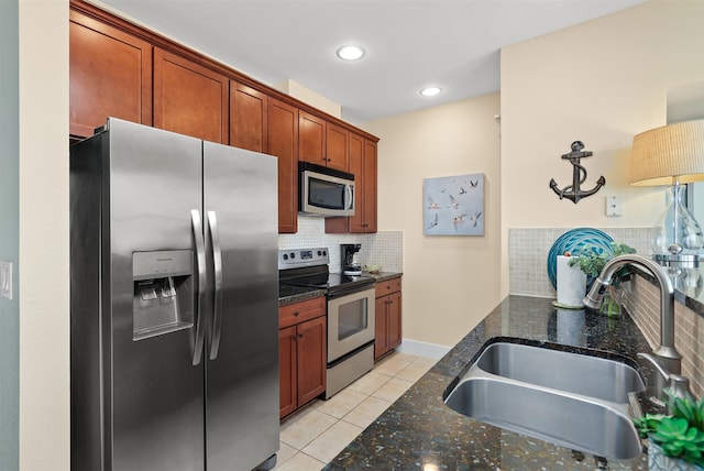 kitchen with appliances with stainless steel finishes, dark stone counters, backsplash, sink, and light tile floors