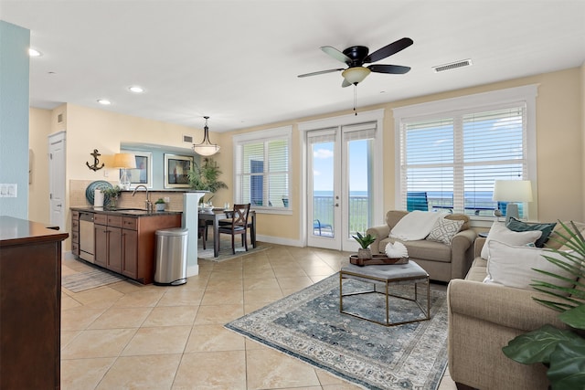 tiled living room featuring a wealth of natural light, sink, ceiling fan, and french doors