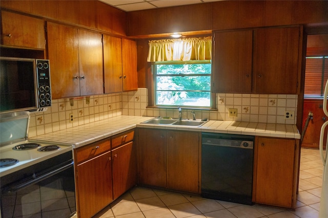 kitchen with backsplash, dishwasher, sink, white electric stove, and tile counters