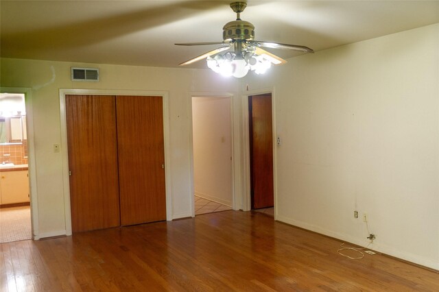 unfurnished bedroom with ceiling fan, wood-type flooring, and a closet