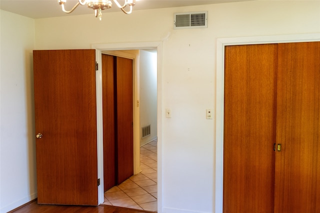 corridor featuring an inviting chandelier and light tile patterned flooring