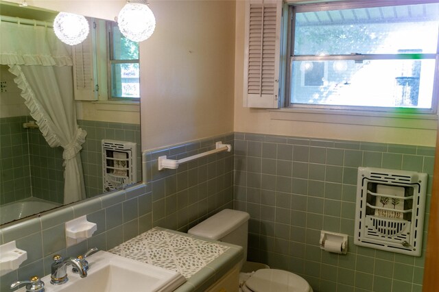 bathroom featuring a shower with curtain, sink, tile walls, and toilet