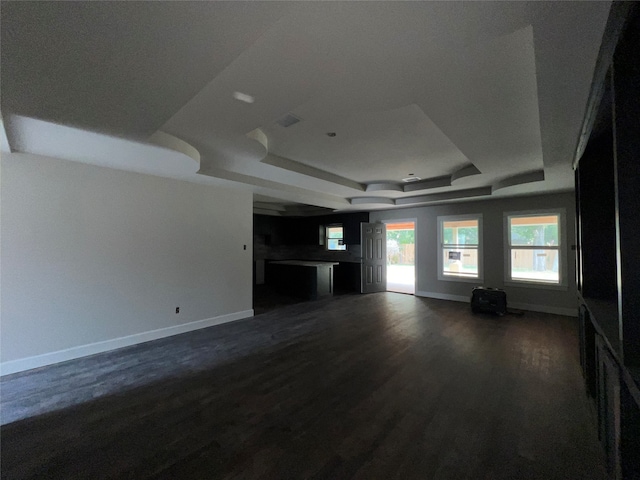 unfurnished living room featuring a raised ceiling and dark hardwood / wood-style flooring