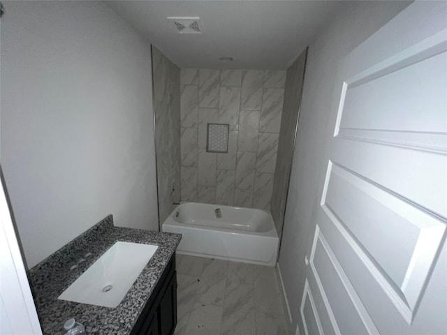 bathroom with tiled shower / bath combo and vanity