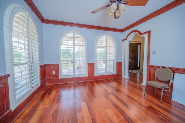 unfurnished room featuring hardwood / wood-style flooring, ceiling fan, crown molding, and decorative columns