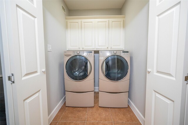 washroom featuring cabinets, light tile patterned floors, and washing machine and dryer