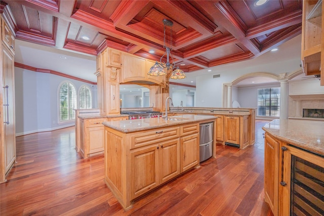 kitchen featuring a center island with sink, a healthy amount of sunlight, hanging light fixtures, and hardwood / wood-style floors