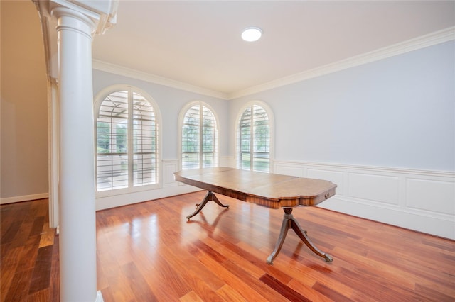 dining area with wood-type flooring, ornamental molding, and decorative columns