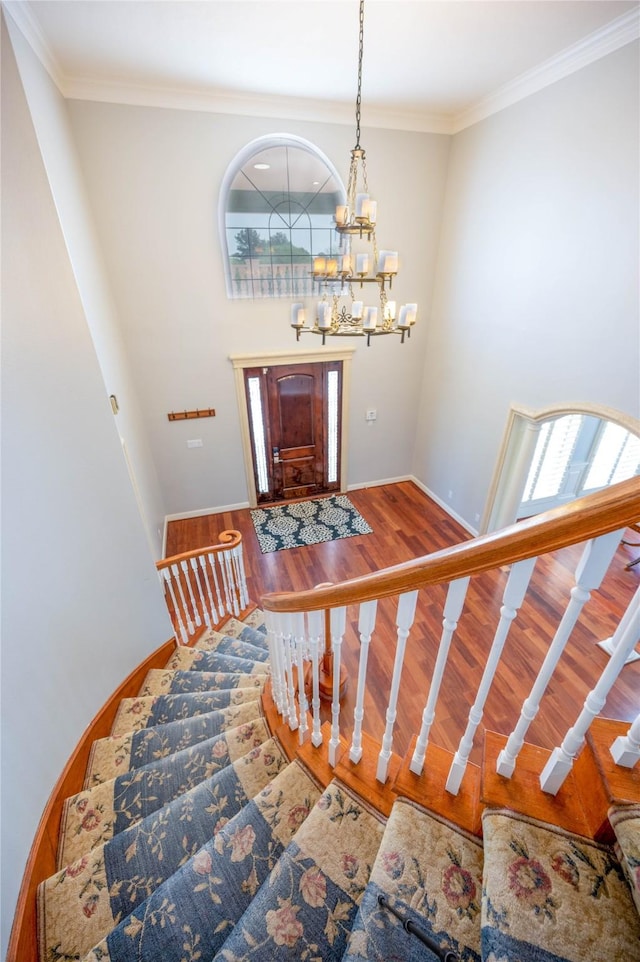 stairway with hardwood / wood-style flooring, an inviting chandelier, and crown molding