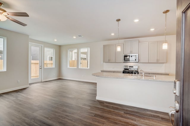 kitchen with light stone countertops, stainless steel appliances, sink, dark hardwood / wood-style floors, and hanging light fixtures